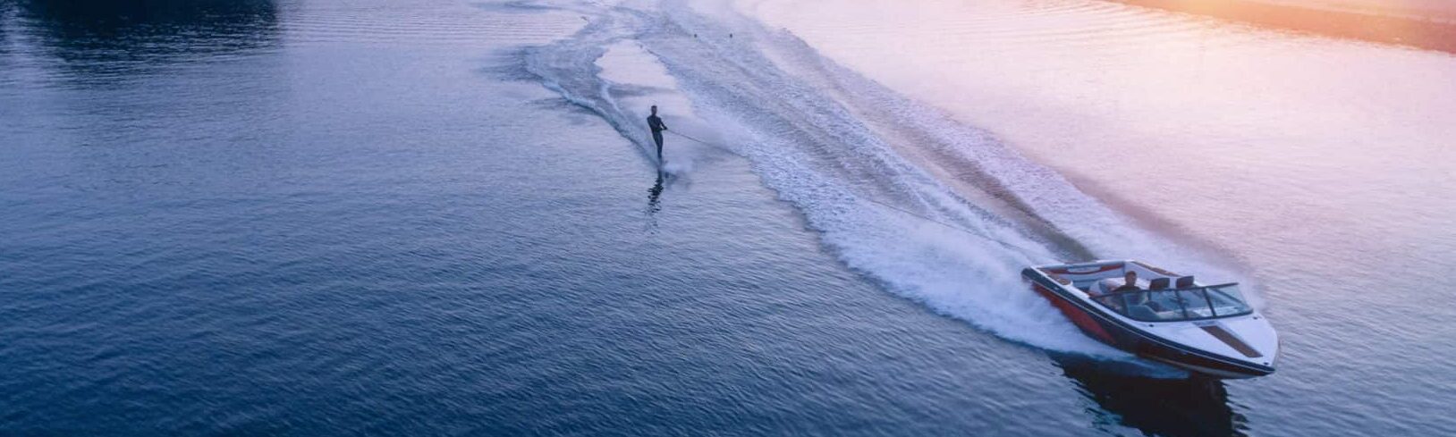 Man water skiiing on lake behind a boat